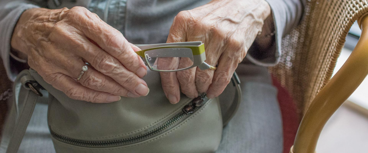 kabelka, okuliare v rukách staršej dámy
